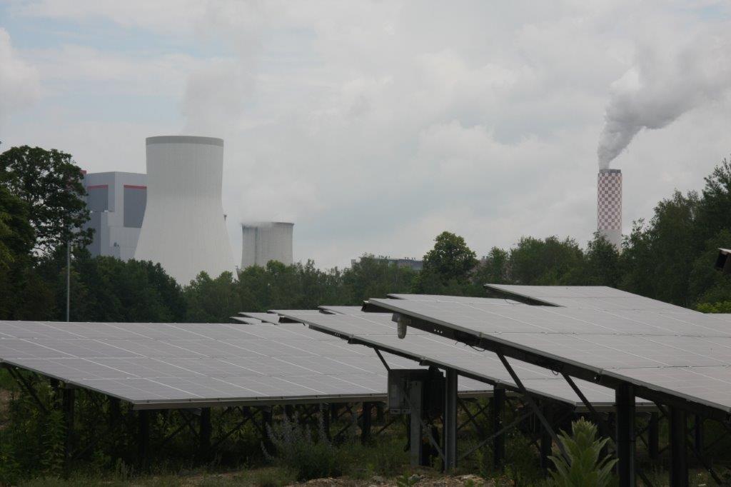 Solarpanele, im Hintergrund Kühltürme eines Braunkohlekraftwerks